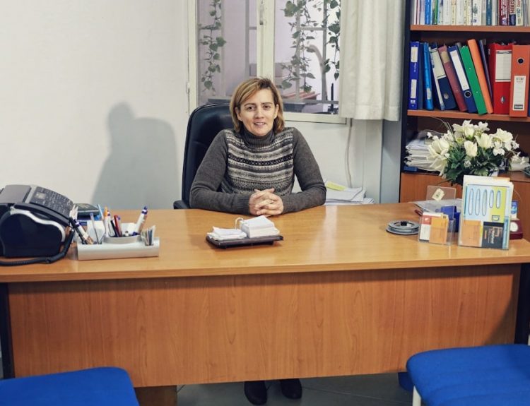 woman sitting beside desk near bookcase with books